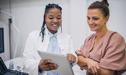 A doctor and patient discussing medical results on a tablet