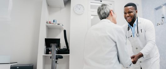 Medical professional and patient smiling and holding hands 
