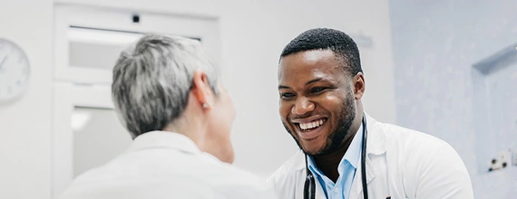 Medical professional and patient smiling and holding hands 