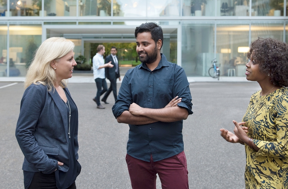 A group of Novartis associates engaged in conversation in front of the Novartis offices at Fabrikstrasse, Basel, Switzerland