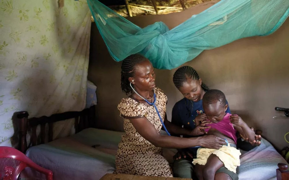 Healthcare worker examines child in malaria-endemic region of rural Kenya.