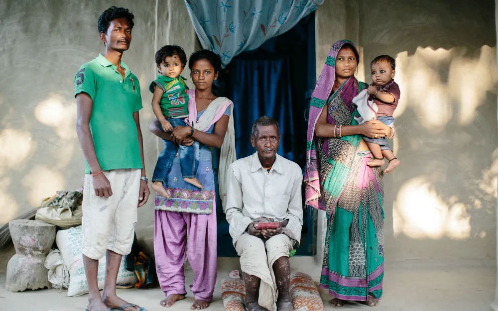 Rameswor sits outside his home in Nepal with his family