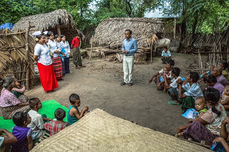 A man teaches a community in Myanmar about leprosy awareness and prevention 