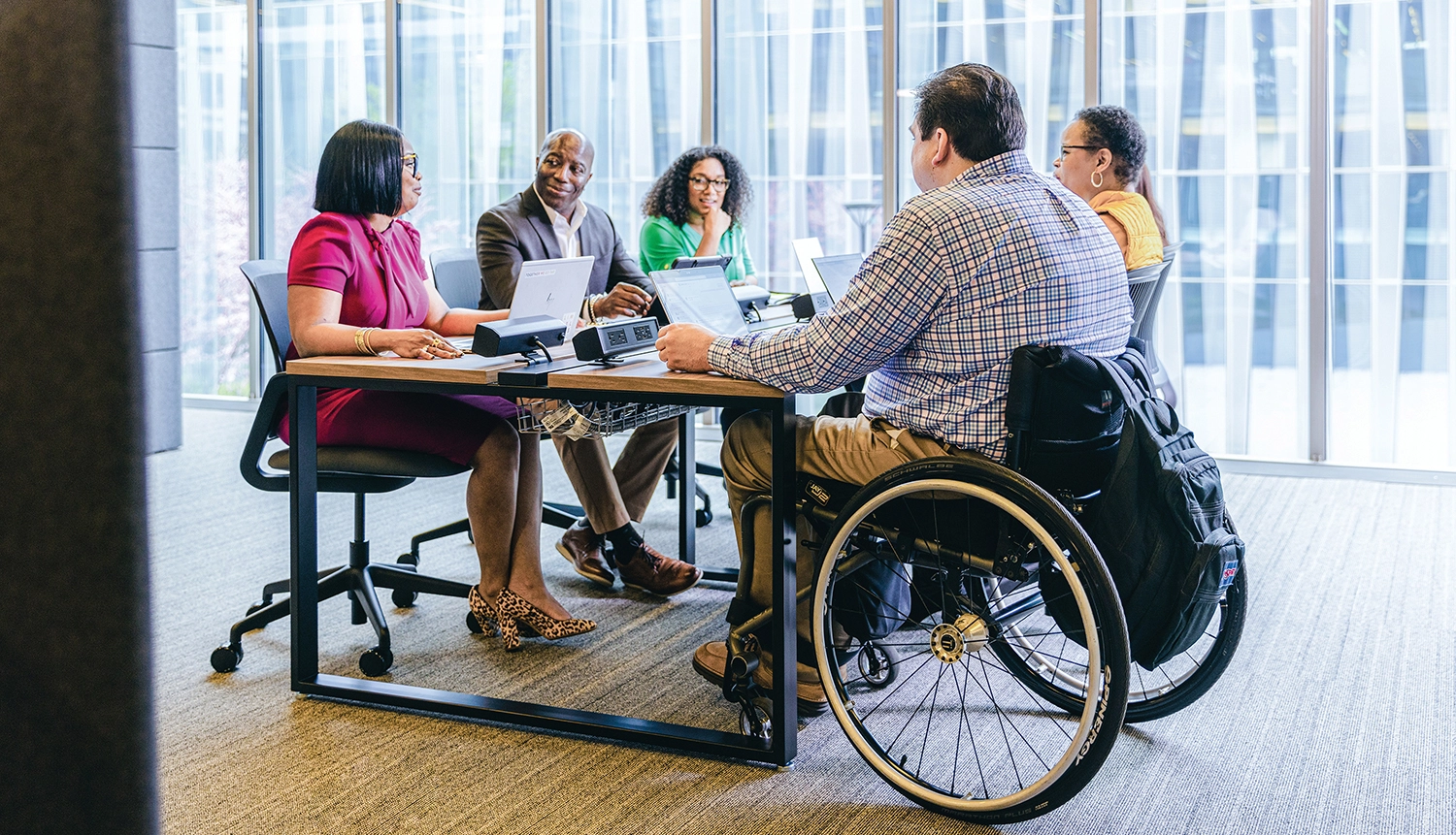 A group of people sitting around a table, in a business meeting