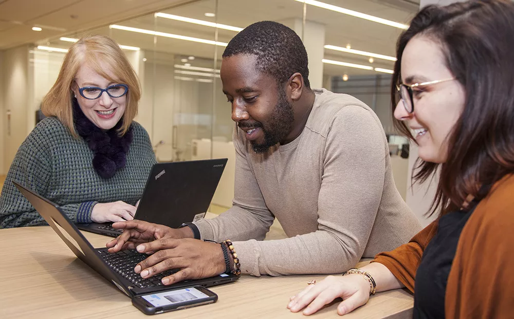 A group of three business people looking at a laptop