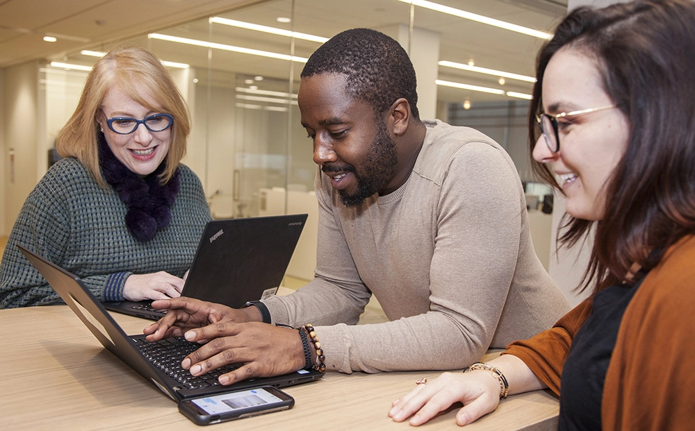 A group of three business people looking at a laptop
