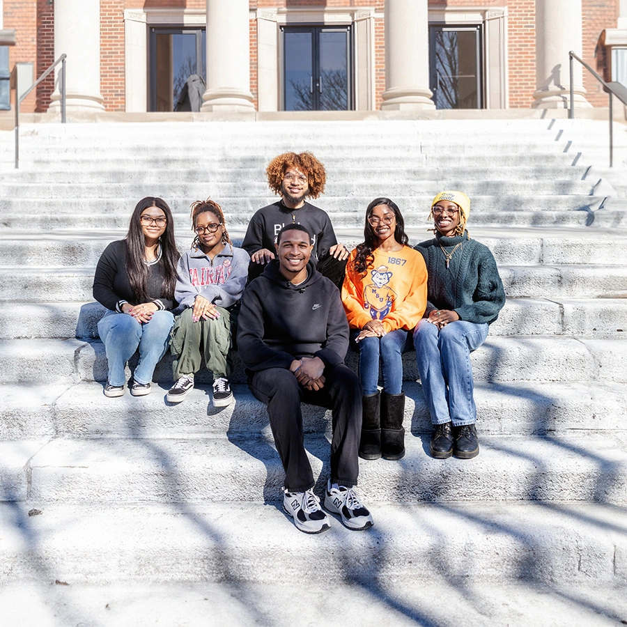 a group of young people sitting on a stair outside in from of a building
