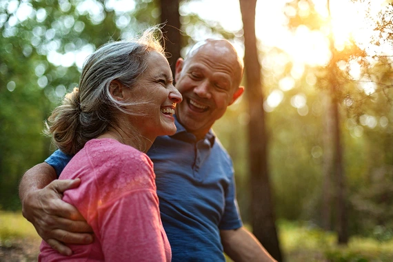 Elderly couple hugging in sunlit forest