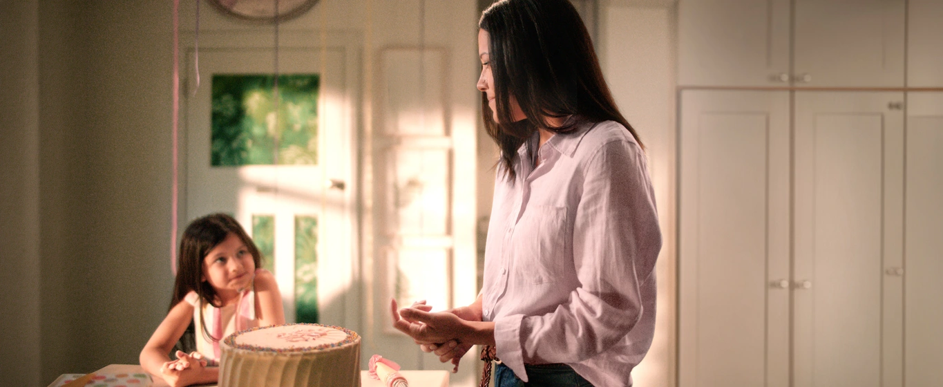 Mother and daughter in their kitchen with the mother looking puzzled and holding her hand