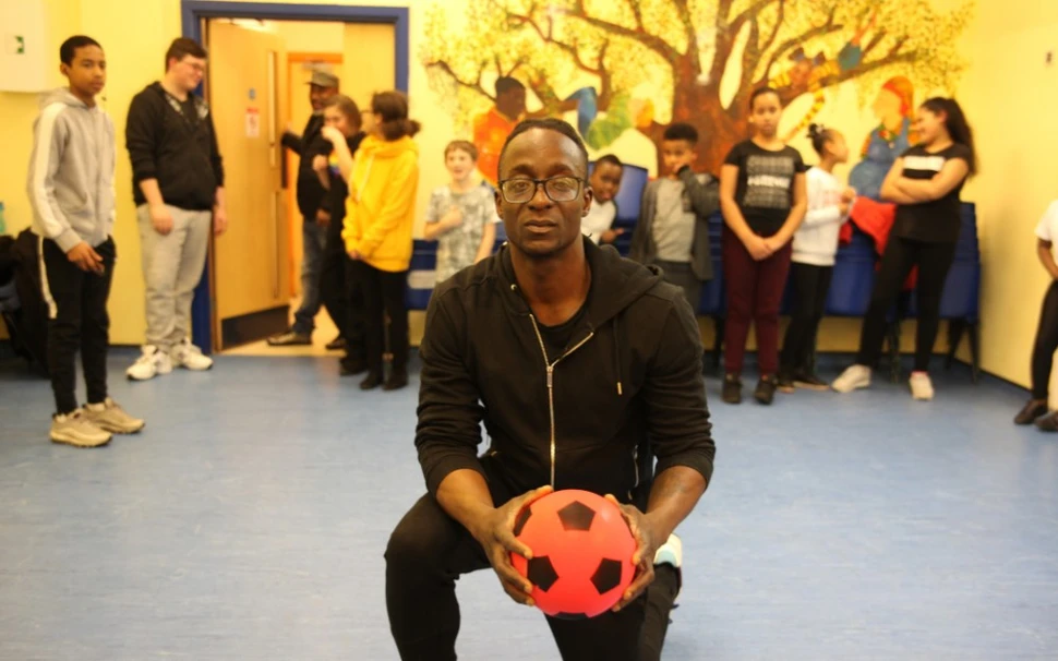 Sickle cell disease patient, Emmanuel, poses with children in UK community center