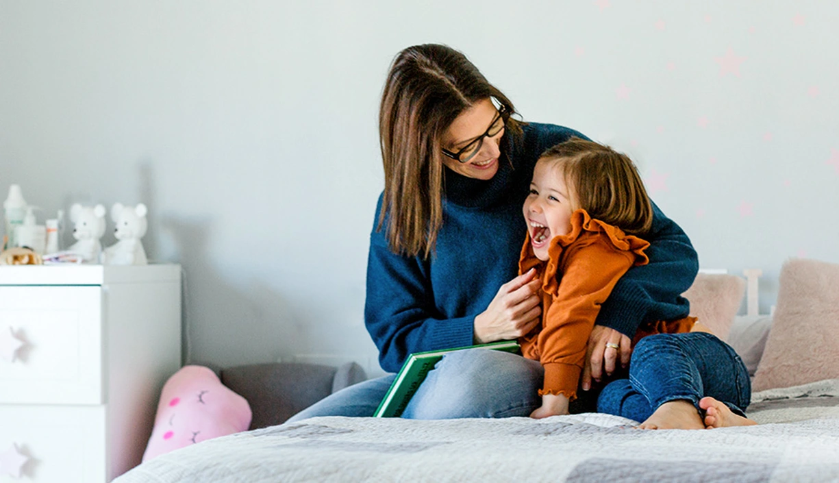 Mother and daughter cuddling on a bed in a kids room