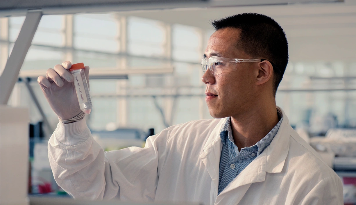 Scientists handling a test tube in a laboratory with protective gear