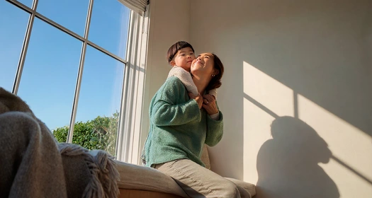 Mother and son cuddling on a couch in front of a window