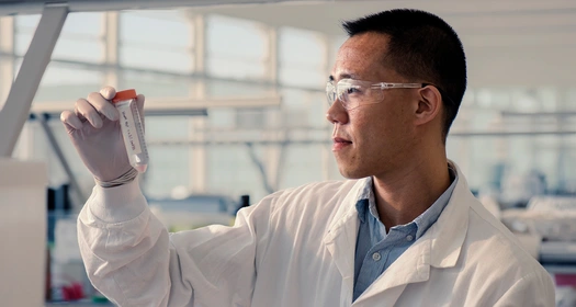 Scientists handling a test tube in a laboratory with protective gear