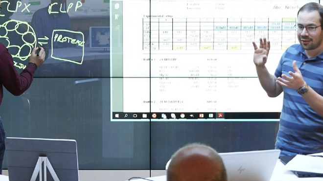 Novartis scientists Edward Oakeley (left) and Mevion Oertli use a plasma screen to present their findings to Novartis researchers.