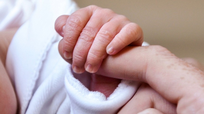 Baby's hand holding parent's finger