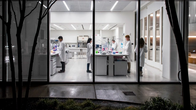Scientists working in a lab at night seen by the outside of the building