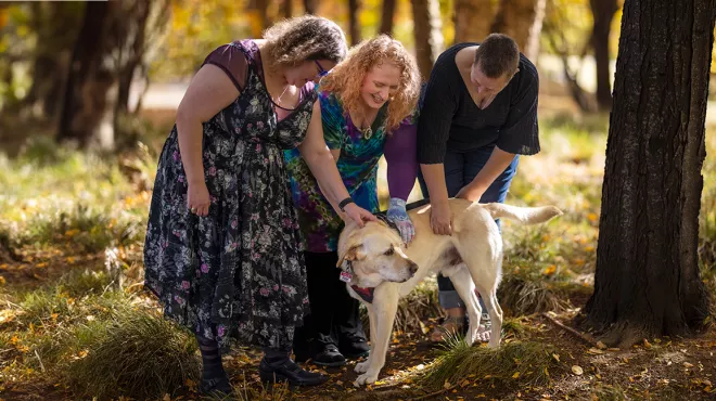Three women petting a dog in a forest