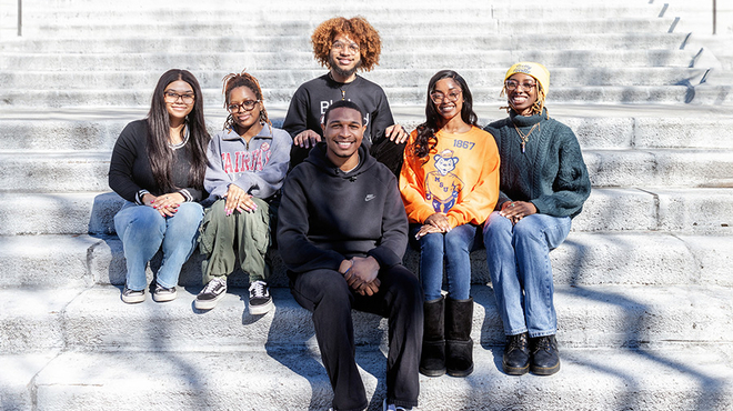 a group of young people sitting on a stair outside in from of a building