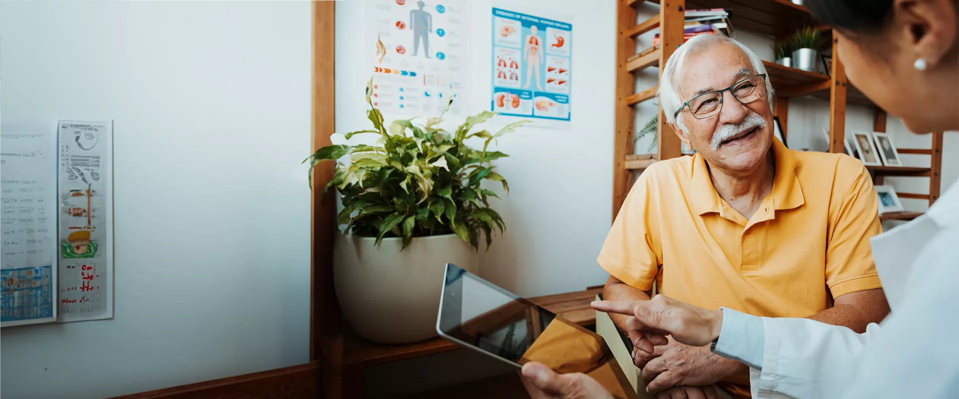 A healthcare professional and senior patient in a conversation using a tablet