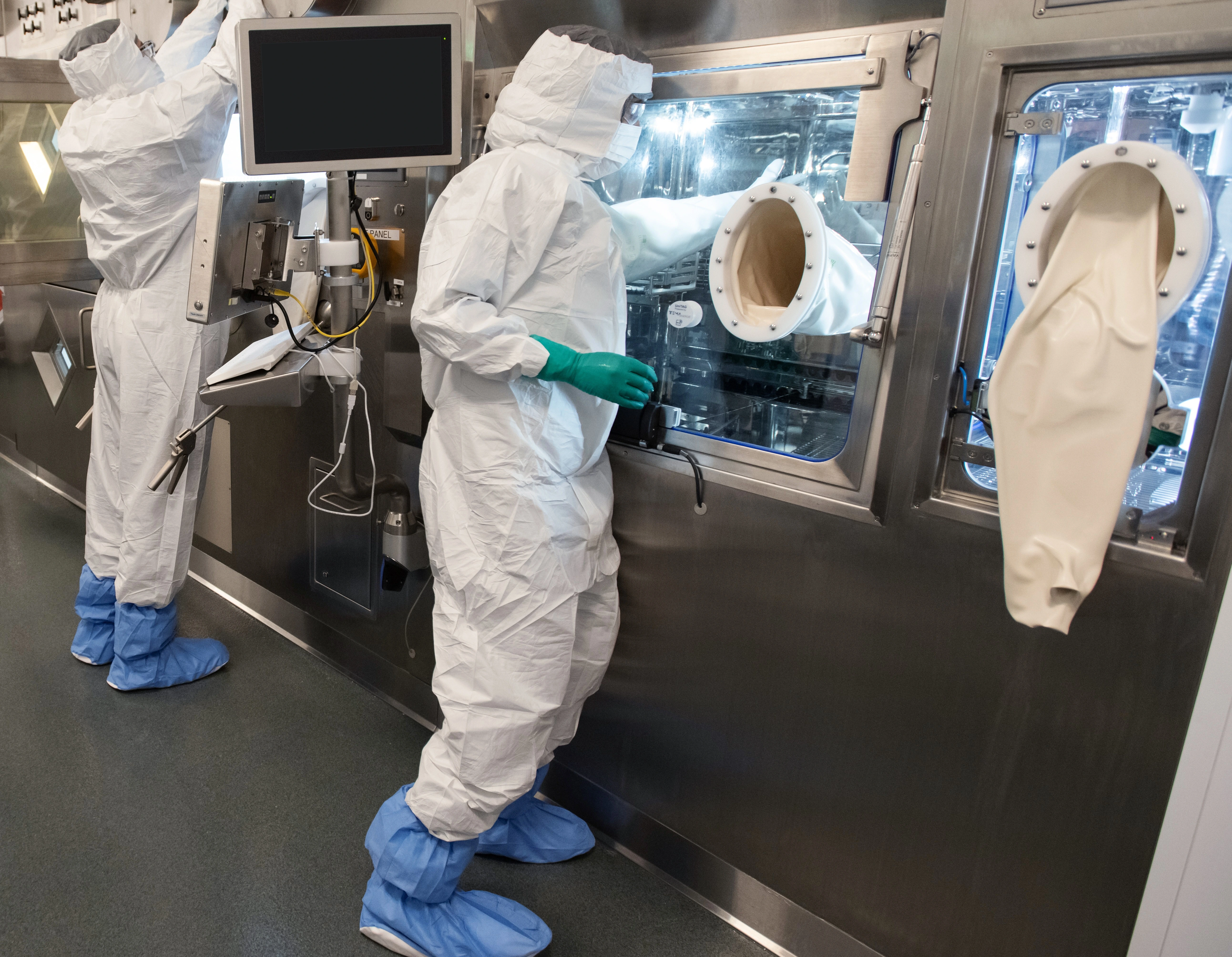 Two associates in full personal protective equipment stand at the production line