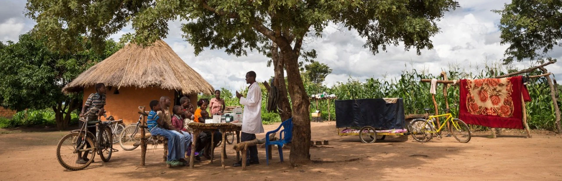 Healthcare worker, Dismus Mwalukwanda, discussing with a group of people in a rural part of Zambia