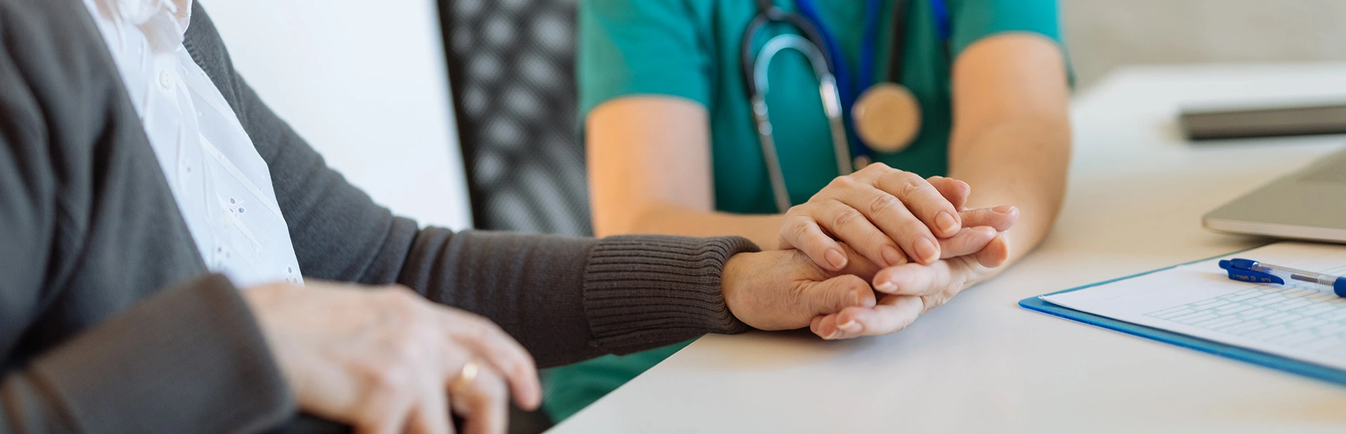 Healthcare professional holding the hands of an elder patient