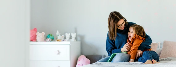 Mother and daughter cuddling on a bed in a kids room