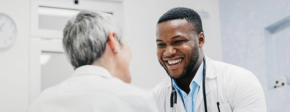 Medical professional and patient smiling and holding hands 