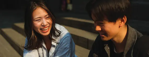 Two persons sitting outside and smiling