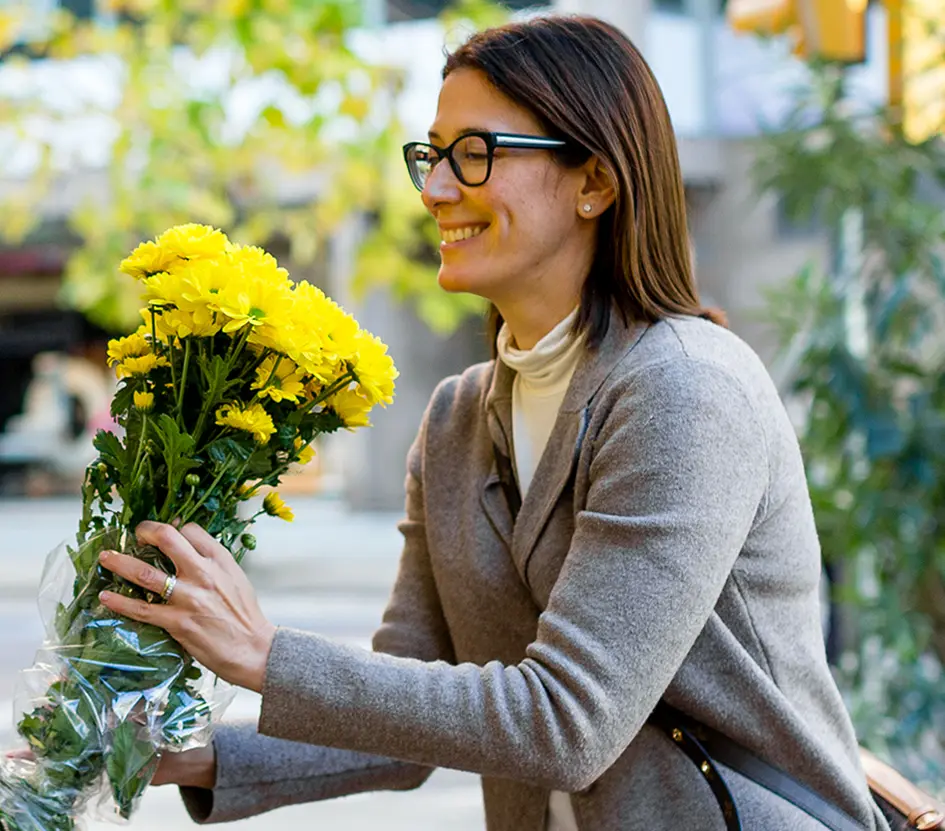 A woman holding a bunch of flowers outside a flowershop