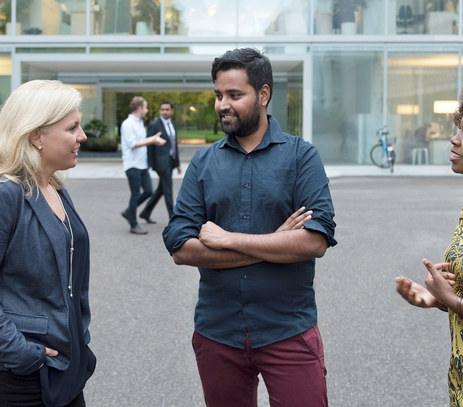 A group of Novartis associates engaged in conversation in front of the Novartis offices at Fabrikstrasse, Basel, Switzerland