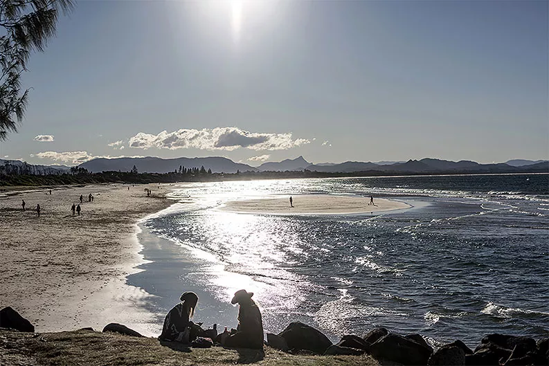 A family enjoys sitting on the beach in Australia.