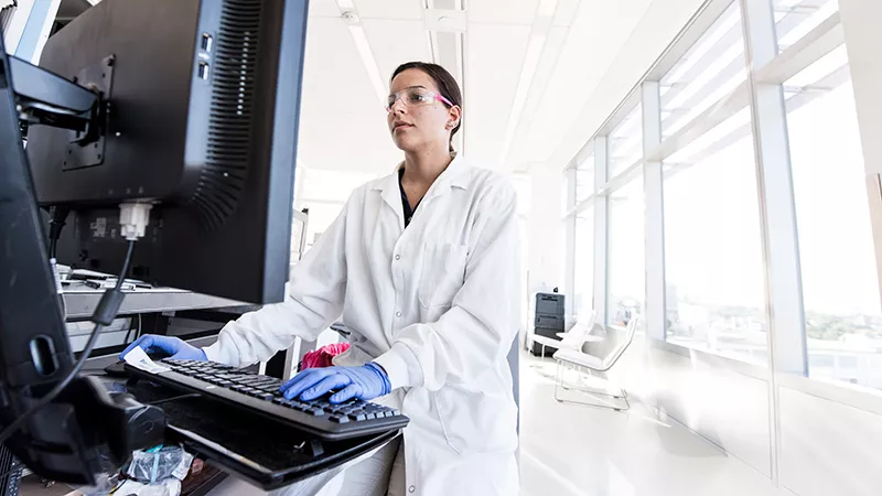 A Novartis data scientist is sitting and working in front of a computer.