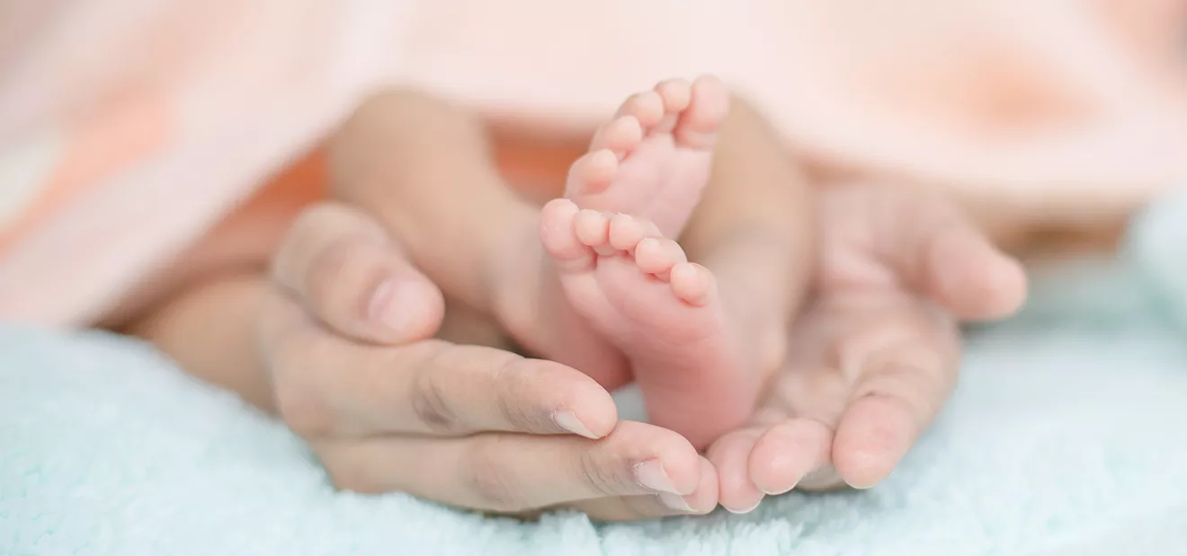 Parent’s hands holding baby feet