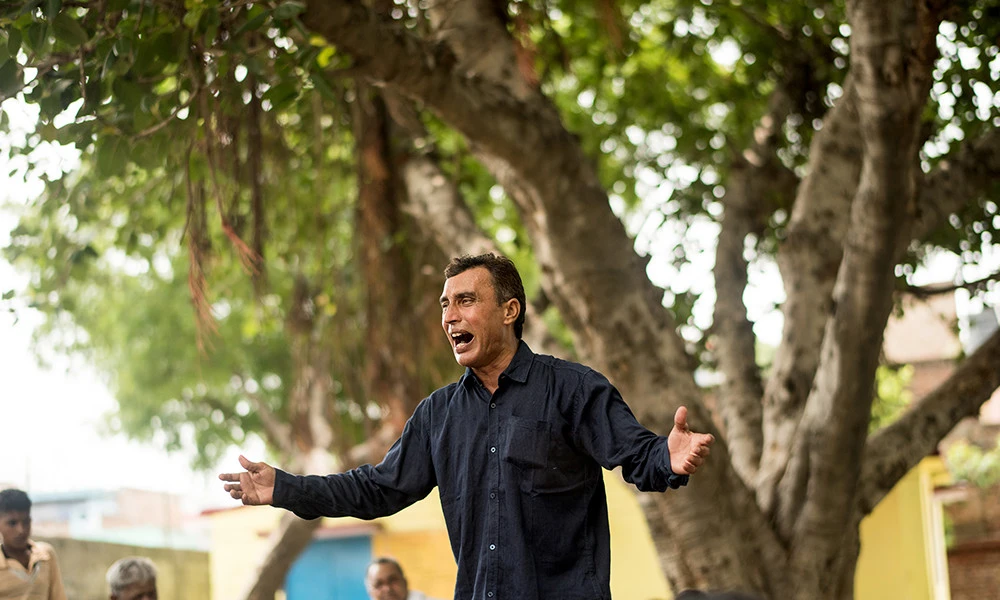 A healthcare worker in India performs a musical act for a crowd in his village.