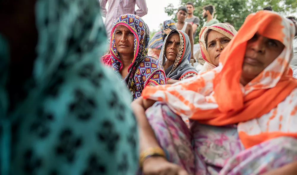 Indian women watch a musical performance in their village