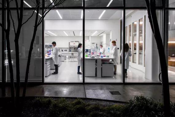 Scientists working in a lab at night seen by the outside of the building