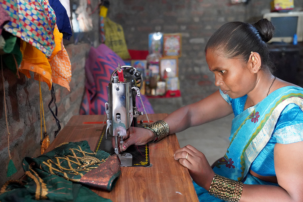 A woman participating in the Championing Sustainable Livelihoods program by Novartis India sits in front of a sewing machine.