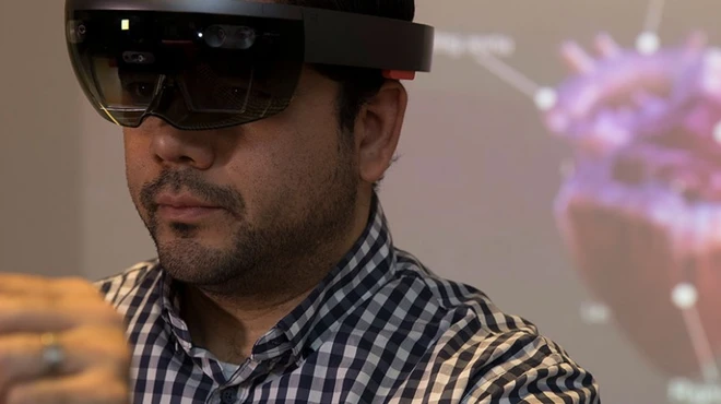 Man wearing AR glasses to manipulate a hologram of a heart