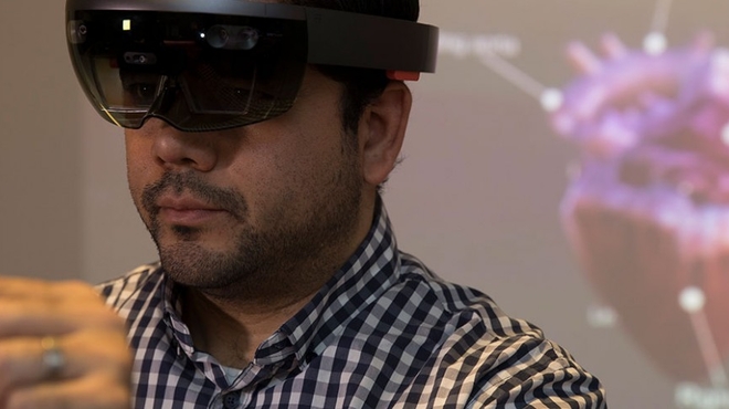 Man wearing AR glasses to manipulate a hologram of a heart