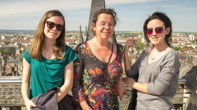 Lauren Abrey and her two daughters posing in front of a city.