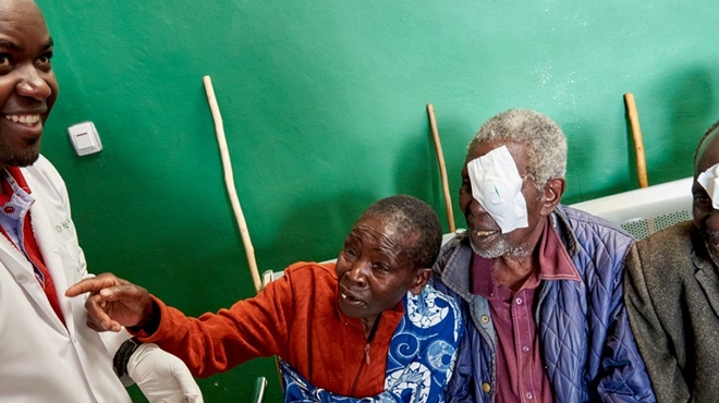 Dr. Theophile Tuyisabe standing next to his patients smiling at him