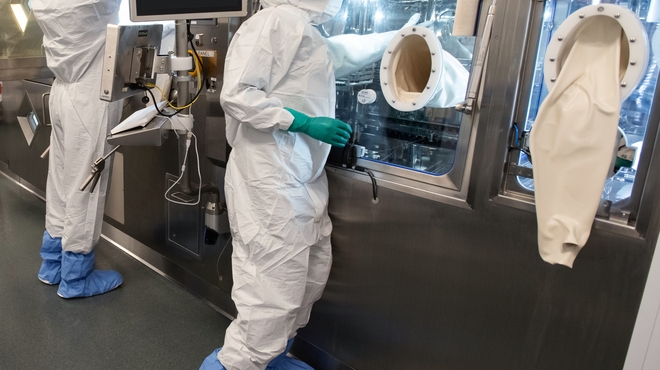 Two associates in full personal protective equipment stand at the production line