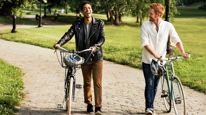 Friends walking with bikes in a park on a sunny day