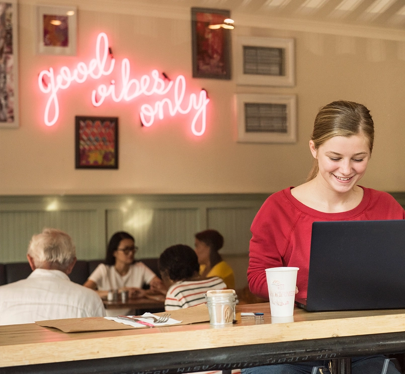 Žena pracujúca v kaviarni za počítačom