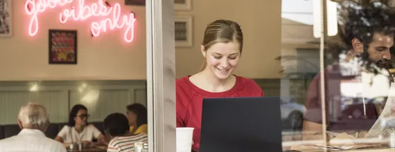 Žena pracujúca v kaviarni za počítačom