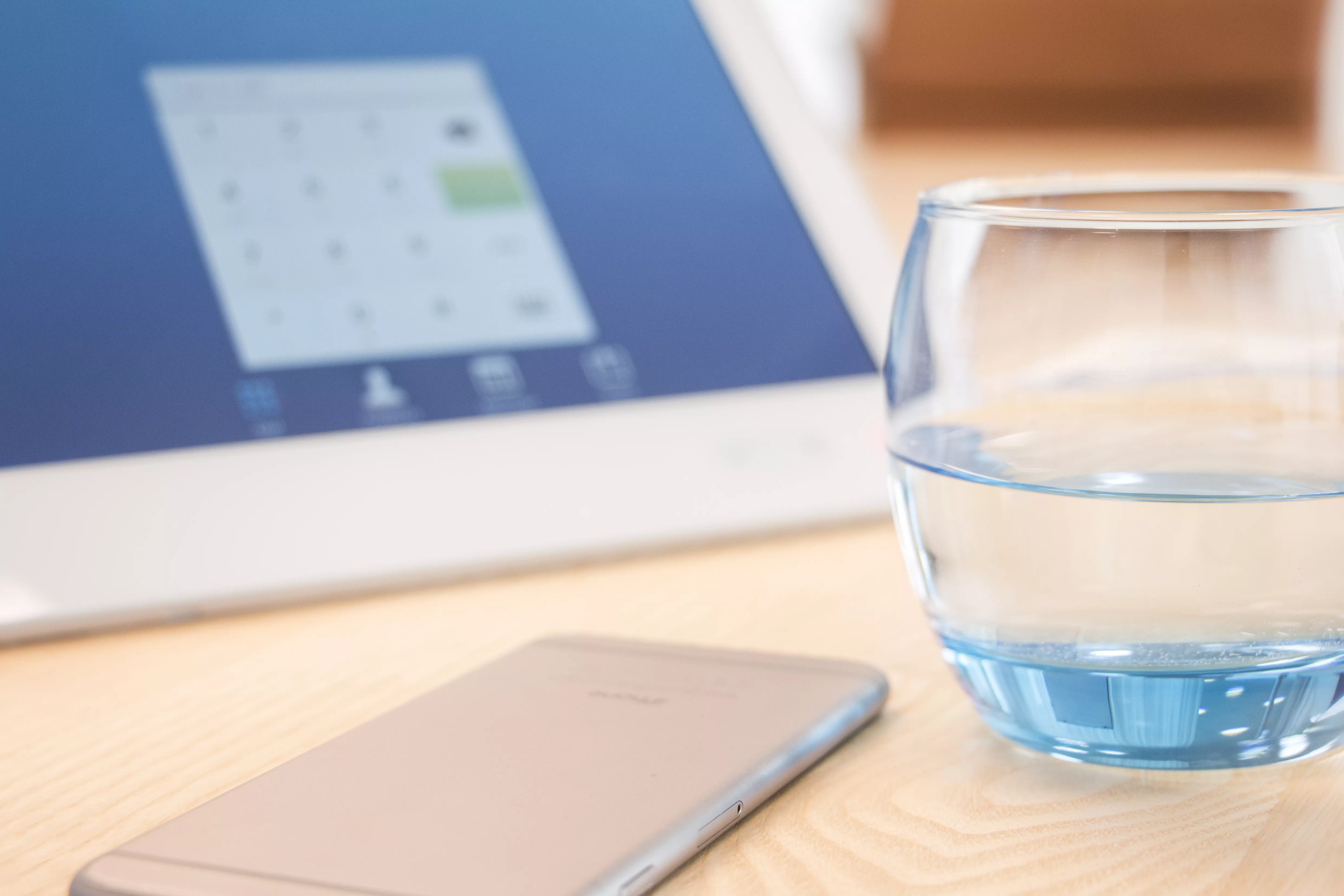 Pracovný stôl s pohárom vody, mobilom a tabletom