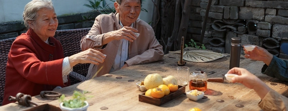 Family enjoying tea together outdoors at a wooden table