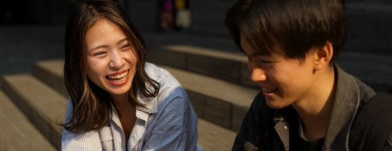 Two people sitting and talking on steps at sunset